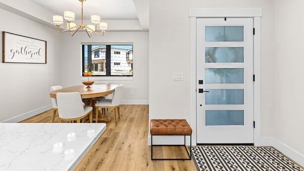 A modern kitchen with a marble countertop, wooden dining table, and chairs.