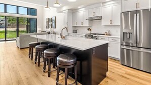A modern kitchen with a large island, stainless steel appliances, and a bar stool seating area.