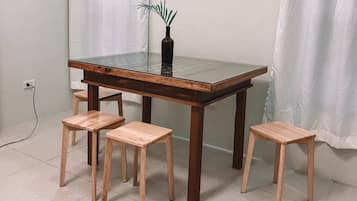 Una mesa de comedor con cubierta de vidrio y cuatro taburetes de madera.