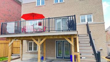 A two-story house with a balcony, a wooden deck, and a staircase leading to the upper floor.