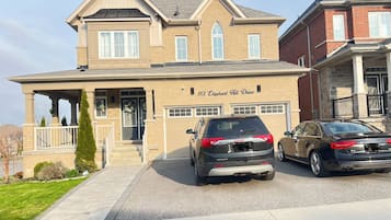 A two-story house with a garage, a driveway, and two parked cars.