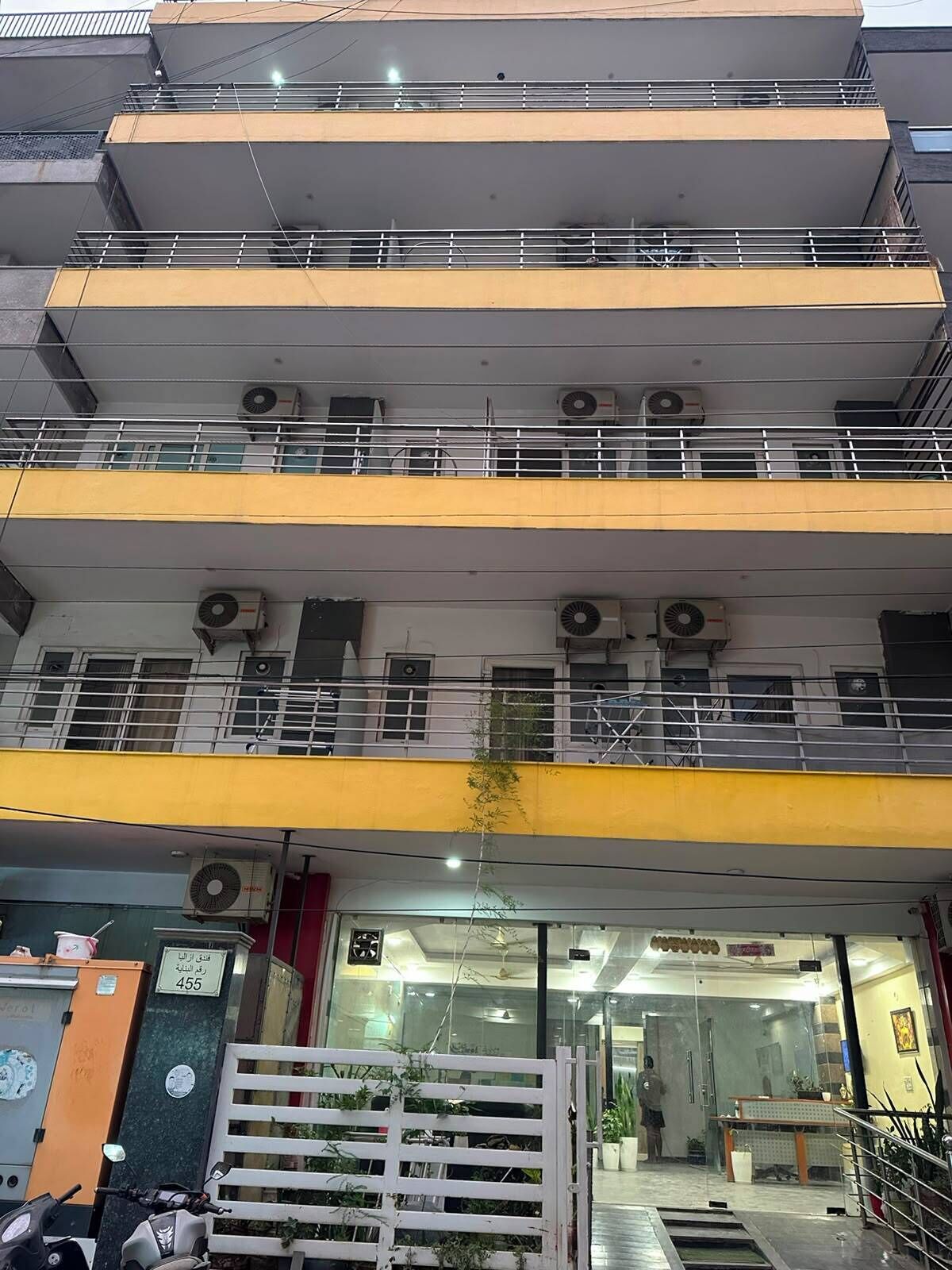 Un immeuble à plusieurs étages doté de balcons, de climatiseurs et d’une entrée sécurisée par un portail.