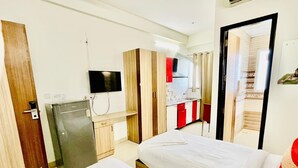 A hotel room with two beds, a TV, a mini-fridge, and a bathroom visible through an open door. - Azalea By Oasis Stays  (Gurugram)
