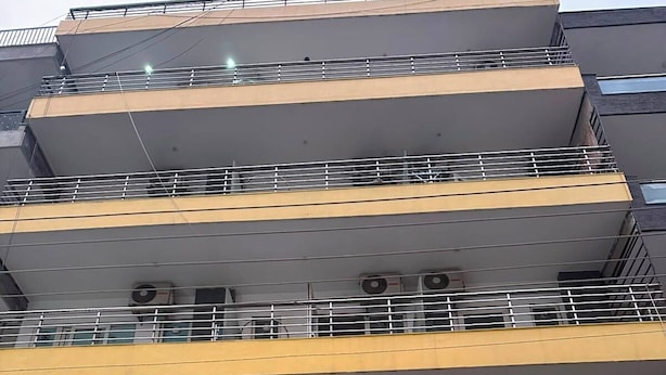 A multi-story building with balconies, air conditioning units, and a gated entrance. - Azalea By Oasis Stays  (Gurugram)