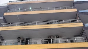 A multi-story building with balconies, air conditioning units, and a gated entrance. - Azalea By Oasis Stays (Gurugram)