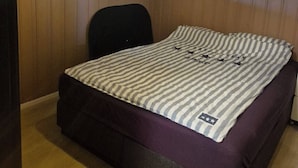 Un dormitorio con cama, ventana y lámpara en el techo.