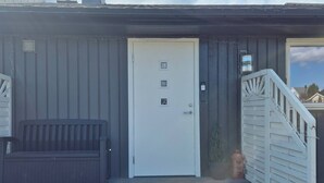 Un edificio con una puerta blanca, un banco y una escalera que lleva a un porche.