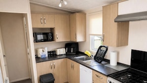 A compact kitchen with wooden cabinets, a microwave, a toaster, a coffee maker, and a stove. - MKRJ LUXURY PLUS – Sleeps 8 - Pet Friendly - LARGE En-suite- mp619 (Camber)