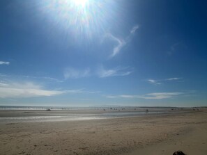 Ein weiter Sandstrand mit blauem Himmel und fernen Bergen.