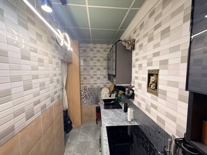 A compact kitchen with white and gray tiles, a small countertop, and a hanging light fixture. - Full private house in heart of Pattaya, 2 min to beach (Pattaya City)