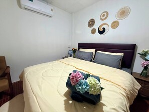 A bedroom with a bed, a chair, a bedside table, a wall-mounted air conditioner, and decorative wall art. - Full private house in heart of Pattaya, 2 min to beach (Pattaya City)