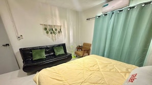 Ein Schlafzimmer mit einem Bett, einer schwarzen Ledersofa, einem kleinen Tisch und einem Sessel.