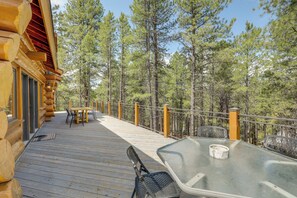A wooden deck with a table and chairs, surrounded by a railing and trees. - Real Log Cabin in Flagstaff with Forest Views (Flagstaff)