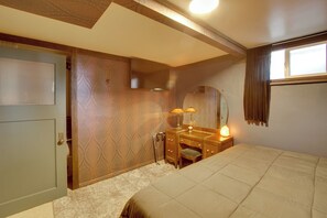 Ein Schlafzimmer mit Bett, Kommode, Spiegel und Fenster.