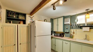 A kitchen with wooden cabinets, a refrigerator, a toaster, and various kitchen utensils.