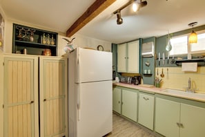 A kitchen with wooden cabinets, a refrigerator, a toaster, and various kitchen utensils.