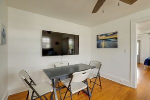 A dining area with a table and chairs, a flat-screen TV mounted on the wall, and a painting above the TV. - 5 Blocks to Sand! Pet-Friendly Unit in Ocean Grove (Ocean Grove)