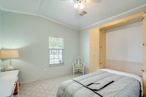A bedroom with a bed, a chair, a lamp, and a window. - Active-Adult Community! Port Charlotte Home, Lanai (Port Charlotte)