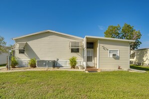 A single-story mobile home with a front porch, a small attached garage, and a well-maintained lawn. - Active-Adult Community! Port Charlotte Home, Lanai (Port Charlotte)