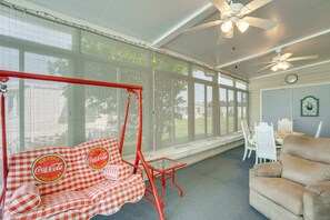 A room with a swing chair, a sofa, a dining table with chairs, and a ceiling fan. - Active-Adult Community! Port Charlotte Home, Lanai (Port Charlotte)