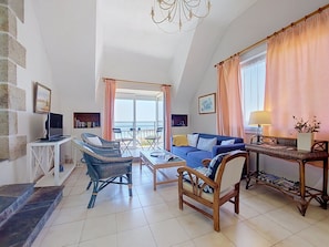 A spacious living room with a balcony, a television, and a sofa.