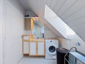 A compact, modern kitchen with a built-in washing machine, a sink, and a mirror above the countertop.