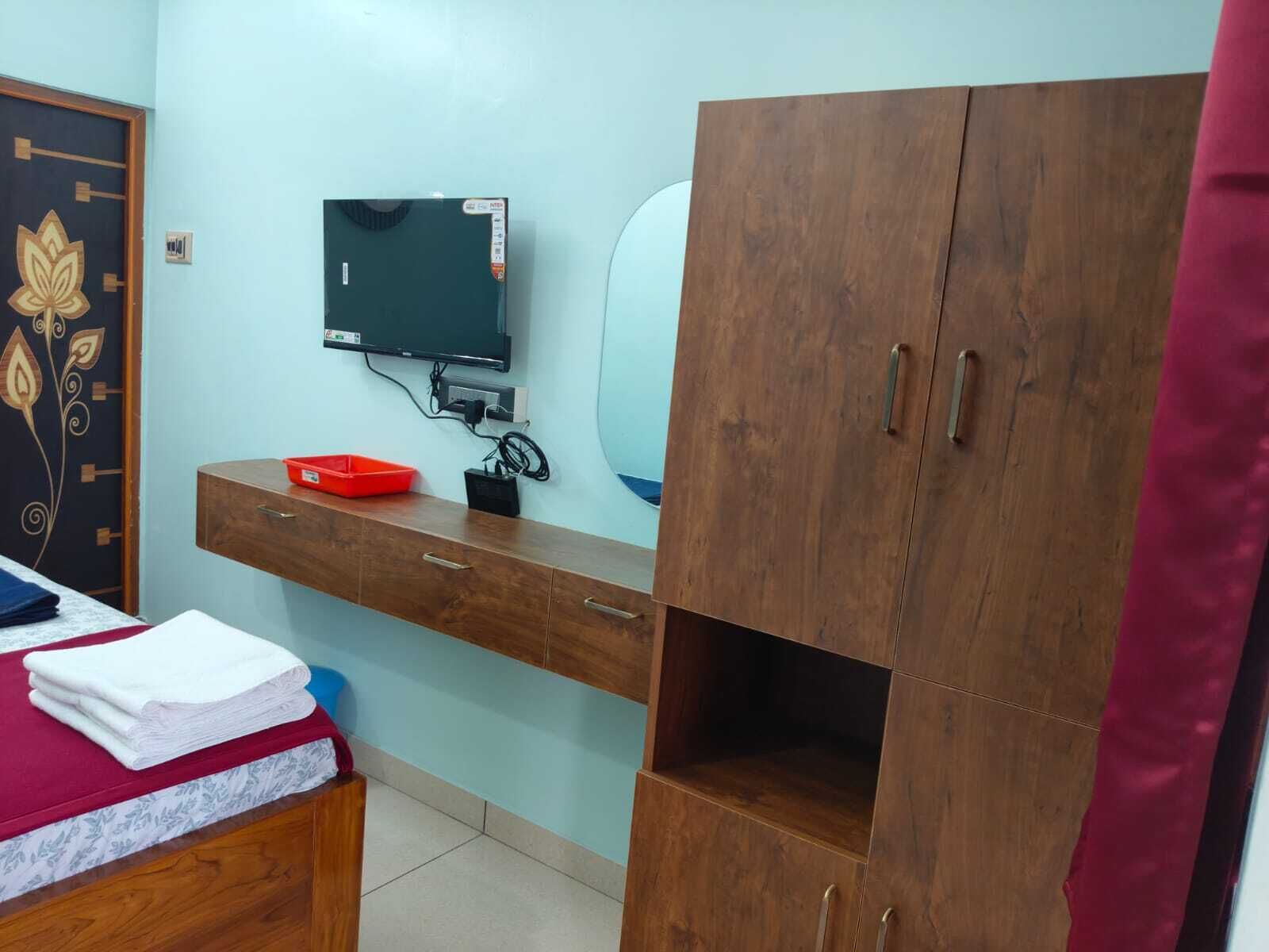 Un dormitorio con cama, armario de madera, televisor y escritorio con espejo.