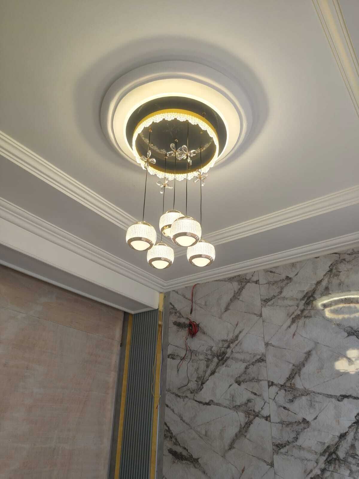 A ceiling with a circular light fixture and hanging spherical lights.