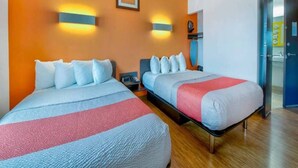 A hotel room with two beds, a nightstand, a wall-mounted lamp, and a door leading to a bathroom. - 2 Full bed | Non-Smoking (EAGLE PASS)