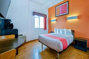 A hotel room with a bed, a desk, a chair, a window with curtains, a wall-mounted picture, and a fireplace. - 1 Queen Bed|Mobil Acc|Tub|Nsmk (EAGLE PASS)