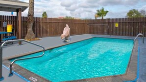 Una piscina rectangular con muelle de madera y barandillas de metal.