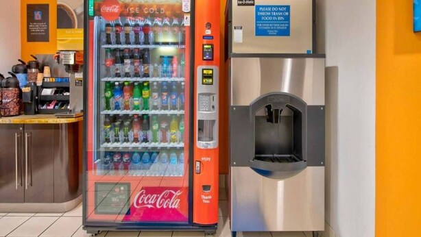 Un distributeur automatique orné du logo Coca-Cola et muni d’un distributeur d’eau.