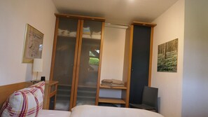 A bedroom with a bed, a chair, a wardrobe, and a painting on the wall. - Vilmblick Vacation Rental - Vacation Rental with a View of Vilm Island (Putbus OT Neuendorf)