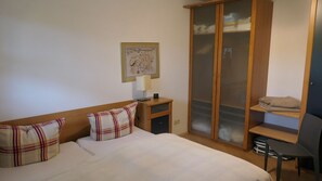 A bedroom with a bed, a nightstand, a wardrobe, a desk, and a chair. - Vilmblick Vacation Rental - Vacation Rental with a View of Vilm Island (Putbus OT Neuendorf)