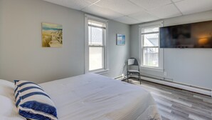 Et hotelværelse med en seng, en stol, et fjernsyn og kunst på væggene.