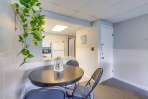 A dining area with a round table, chairs, a hanging plant, and a view into a kitchen. - Walk to Beach, Boardwalk, Restaurants: Asbury Park (Ocean Grove)