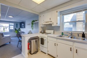 A modern kitchen with white cabinets, a built-in oven, a sink, and a window with a view of the outside. - Walk to Beach, Boardwalk, Restaurants: Asbury Park (Ocean Grove)