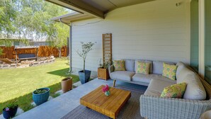 Eine überdachte Terrasse mit einer Couch, einem Couchtisch und Topfpflanzen.