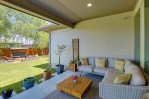 Eine überdachte Terrasse mit einer Couch, einem Couchtisch und Topfpflanzen.