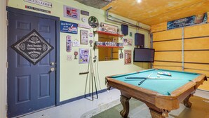 A pool table in a room with a blue door, various posters, and a television on the wall. - Hot Tub & Game Room! Wooded Retreat in Blue Ridge (Blue Ridge)