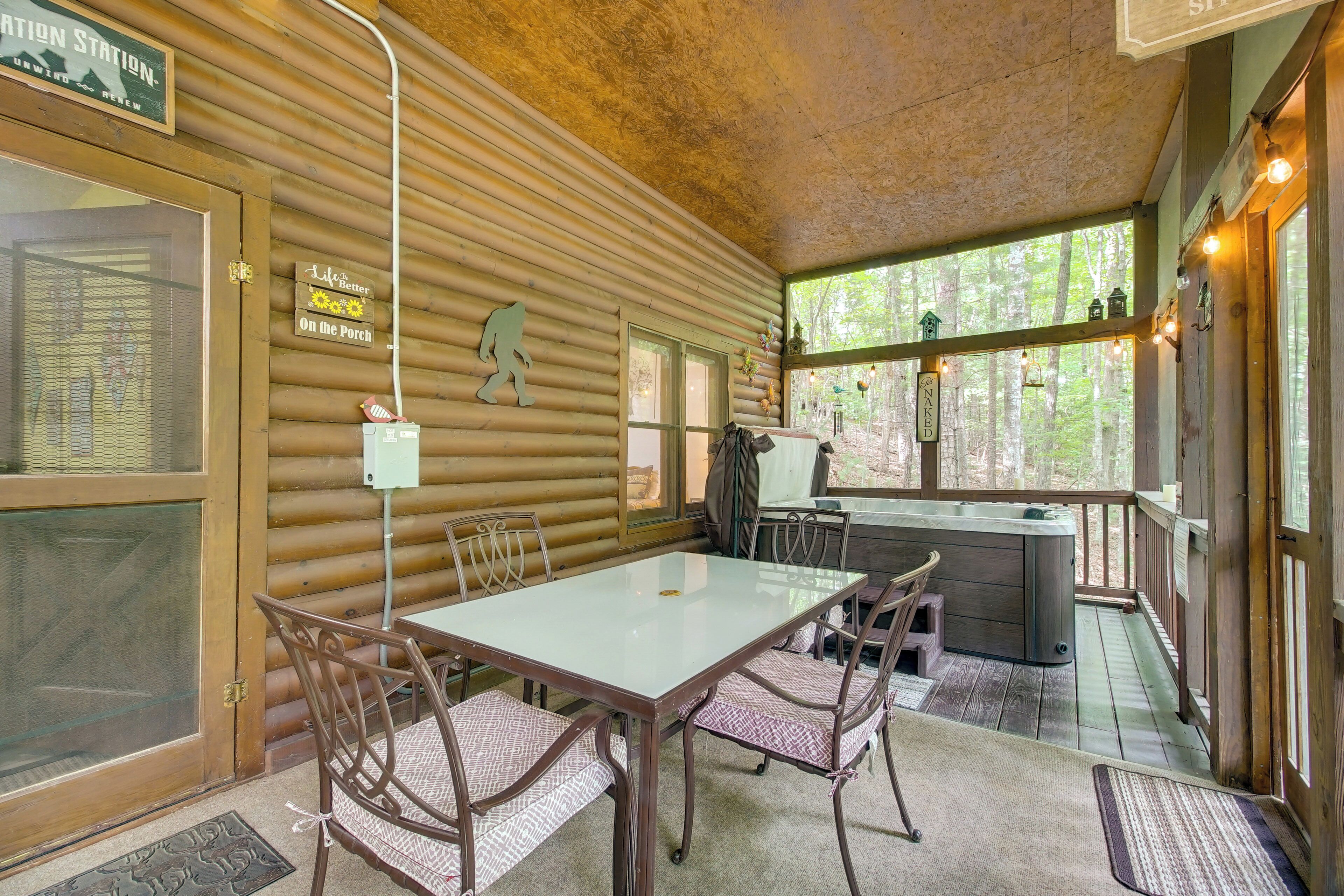 Ein Holzblock-Interieur mit Essbereich, Whirlpool und Veranda mit Blick auf den Wald.