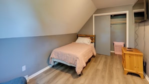 Una camera da letto con un letto, una cassettiera in legno, un armadio e una televisione montata a parete.