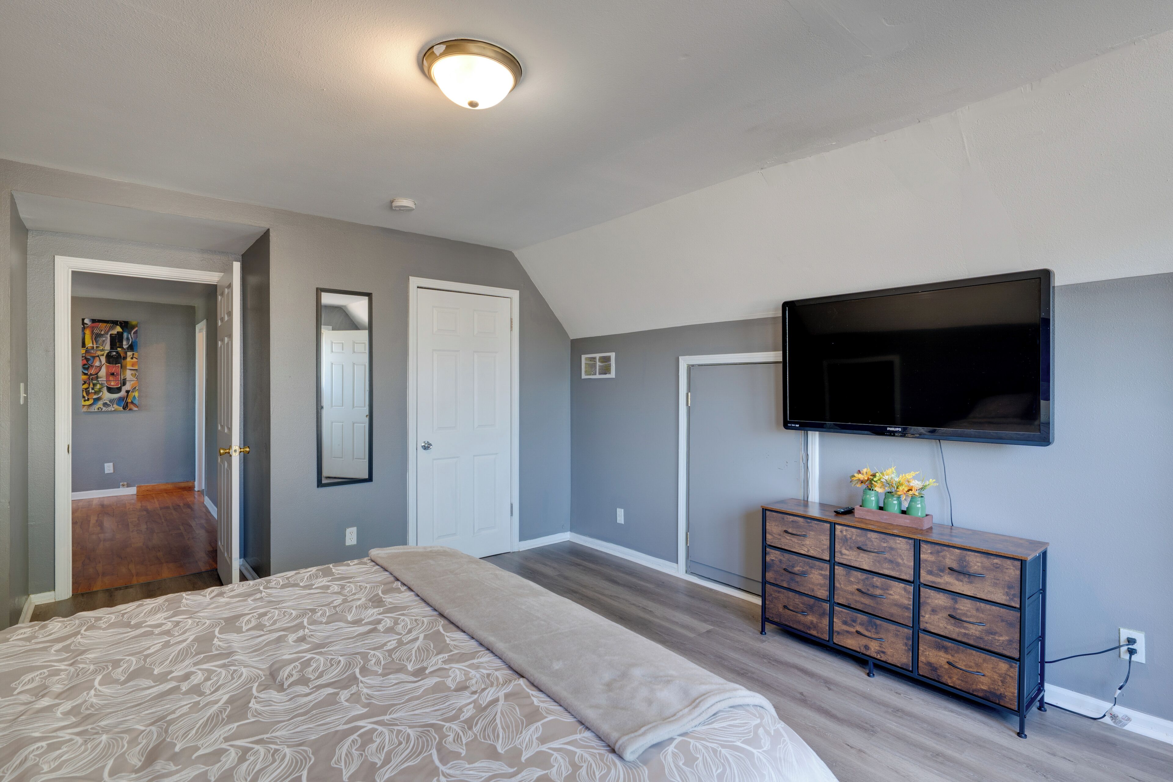 Ein Schlafzimmer mit Bett, Kommode, Fernseher und Bildern an der Wand.