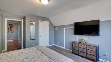 Ein Schlafzimmer mit Bett, Kommode, Fernseher und Bildern an der Wand.