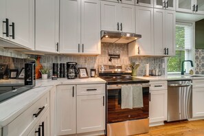 Una cocina moderna con armarios blancos, electrodomésticos de acero inoxidable y piso de madera.