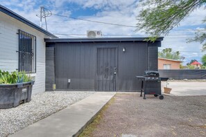 Eine Garage mit einer schwarzen Tür, einem Grill und einem Blumentopf.
