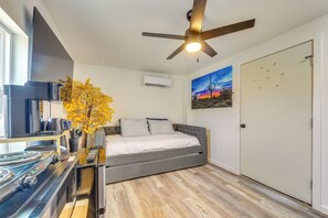 Ein Schlafzimmer mit Bett, Deckenventilator, Gemälde und einer Tür.