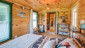 L'interno di una baita di legno con un letto, una scrivania e una libreria.