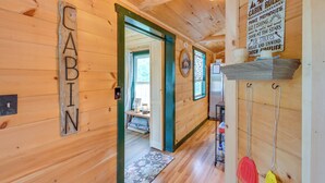 A wooden cabin interior with a sign reading 'CABIN' on the wall, a door leading to a room, and a sign with outdoor activities.