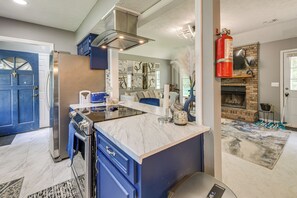 A kitchen with a marble countertop, blue cabinets, a built-in oven, and a fireplace. - 9 Mi to Uptown Columbus! Family Home w/ Yard (Columbus)